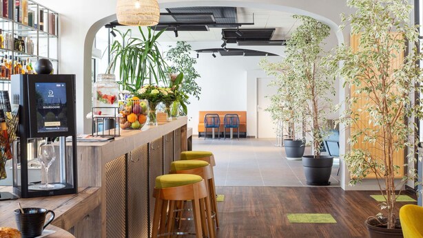 A modern bar area with a wine cooler, bar stools, and a variety of plants. - Mercure Millau (Millau)