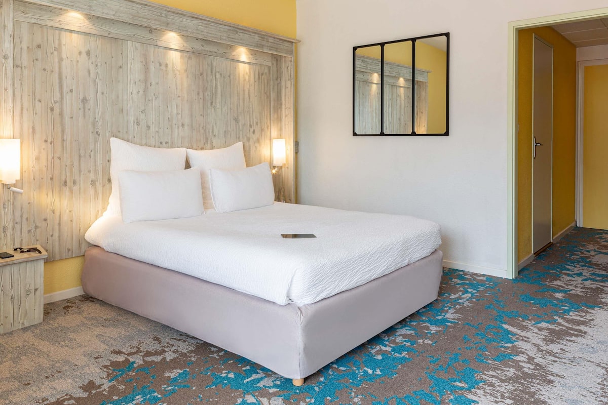 A neatly made bed with white linens, a wooden headboard, and bedside lamps.