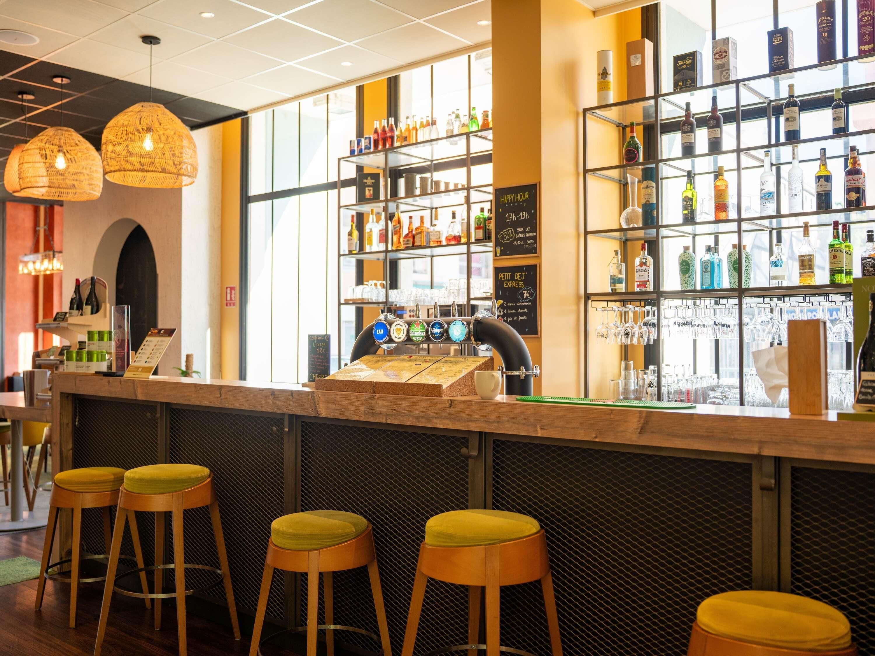 A bar area with stools, a bar counter, and shelves of bottles.
