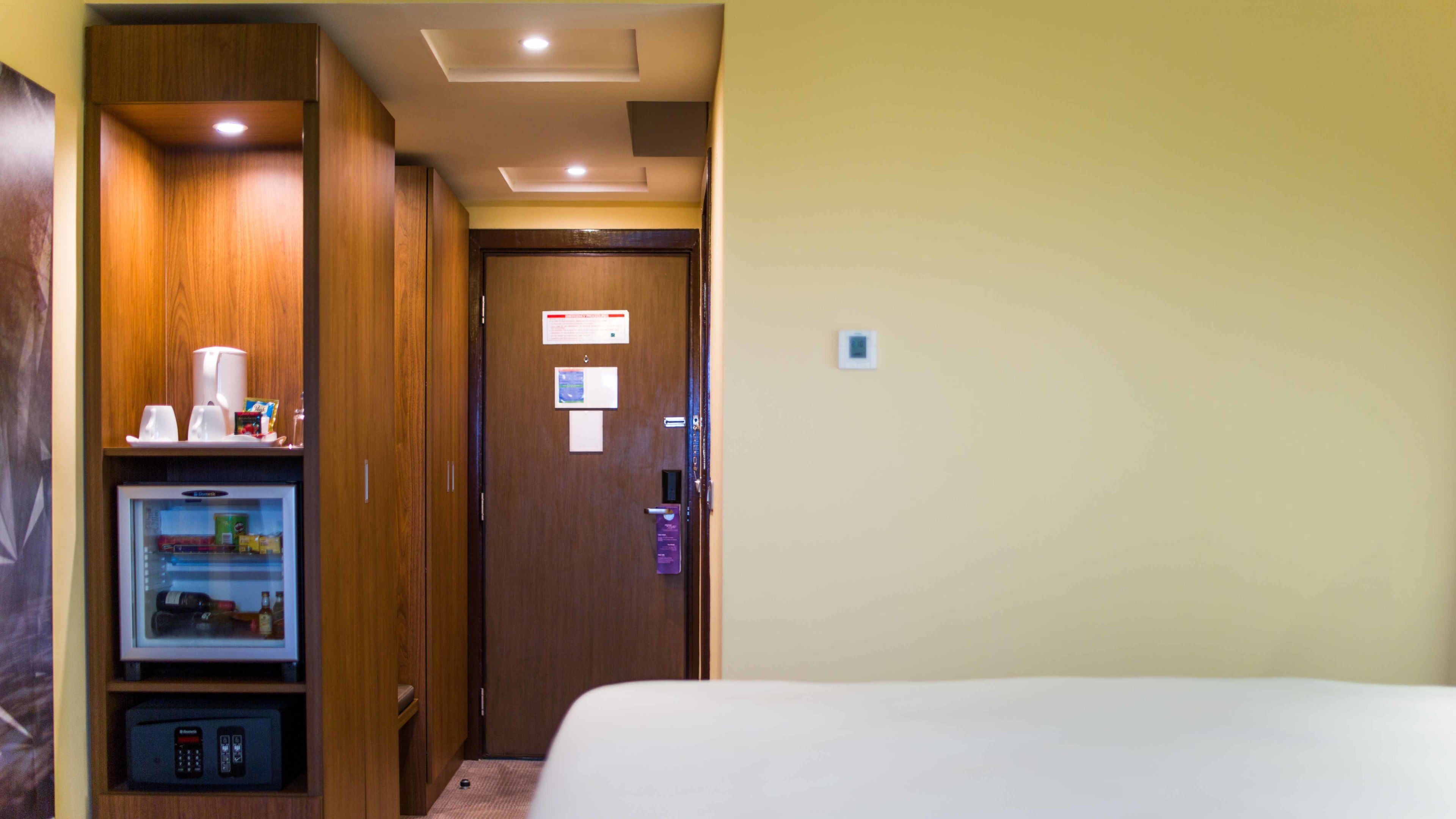 Une chambre d’hôtel équipée d’un lit, d’un minibar, d’une télévision et d’une porte avec une pancarte.