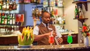 A bartender at a bar with a variety of bottles and glasses in the background.