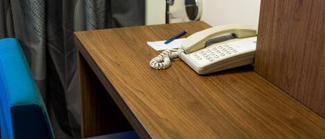 Un bureau en bois avec un téléphone, un stylo et une feuille de papier.