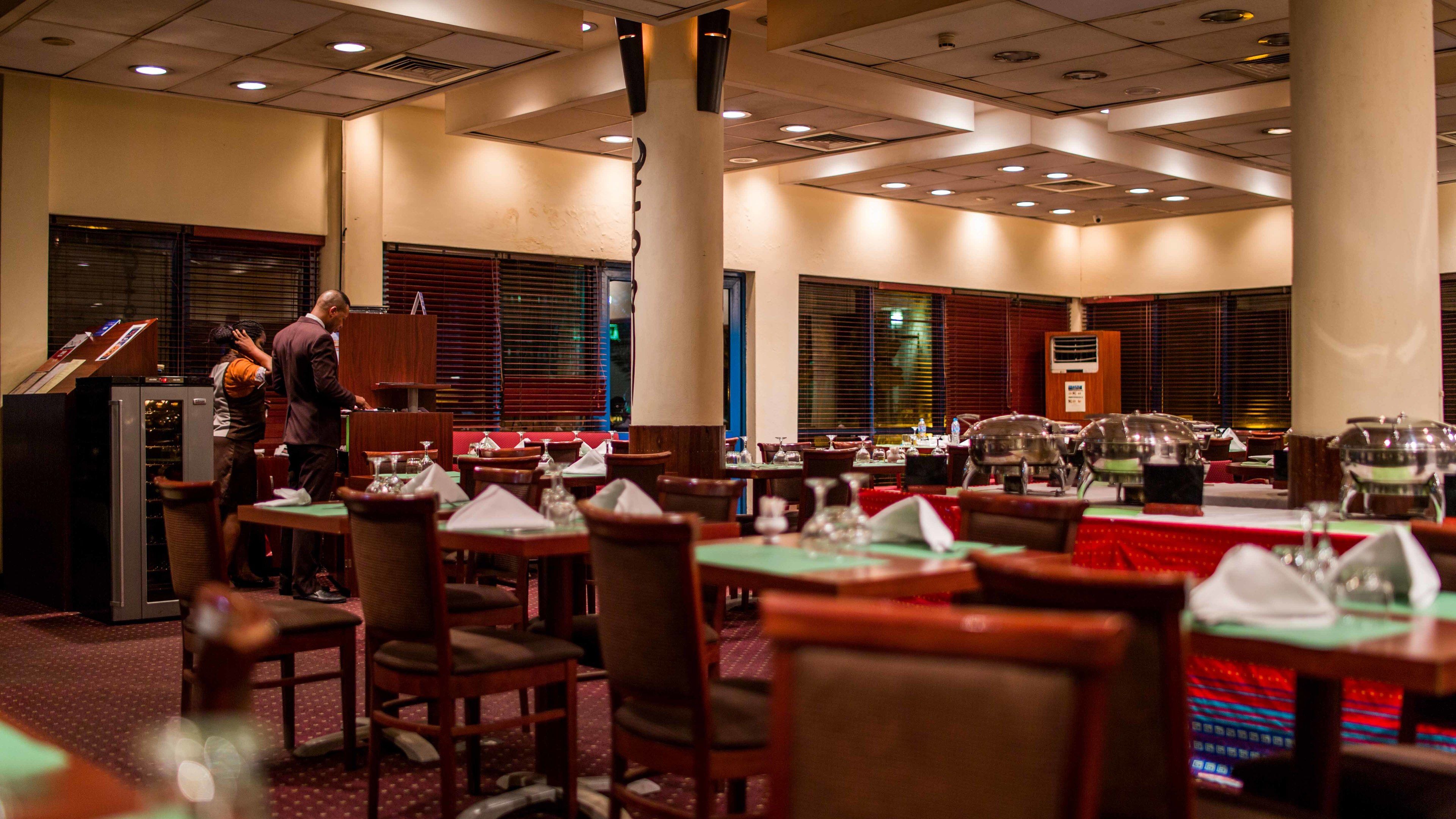 A restaurant with multiple tables, chairs, and a buffet area.