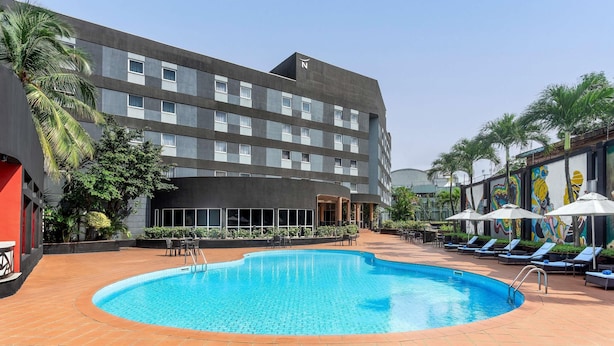 A hotel with a swimming pool, outdoor seating, and a mural on the building.
