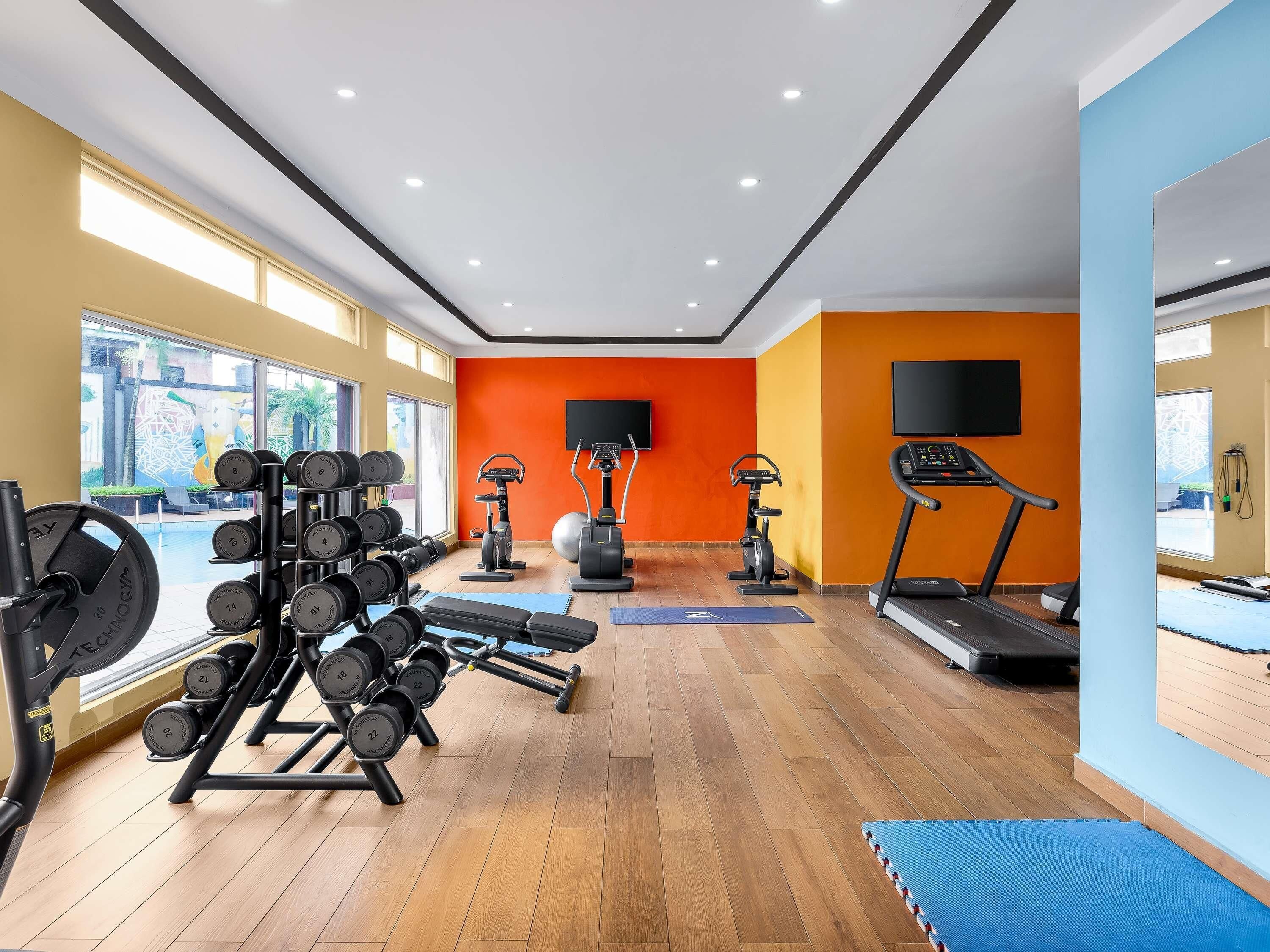 A gym with exercise equipment, a treadmill, and a large window.