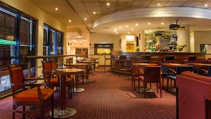 A restaurant with a bar area, multiple seating options including tables and chairs, and a patterned carpet.