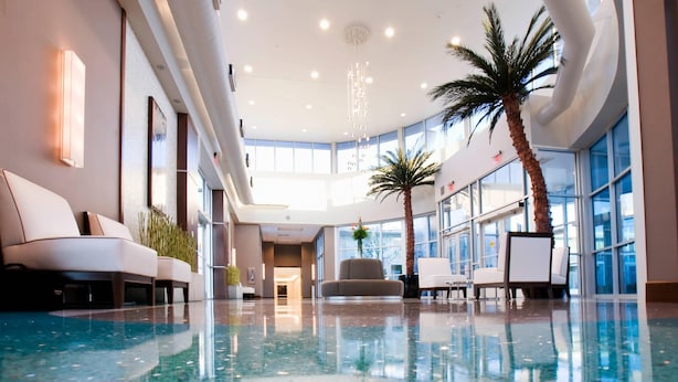 A spacious indoor lobby with a reflective floor, seating areas, and large windows allowing natural light. - Oasis Hotel & Conv. Center, an Ascend Collection Hotel (Springfield)