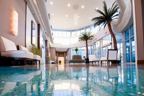A spacious indoor lobby with a reflective floor, seating areas, and large windows allowing natural light. - Oasis Hotel & Conv. Center, an Ascend Collection Hotel (Springfield)