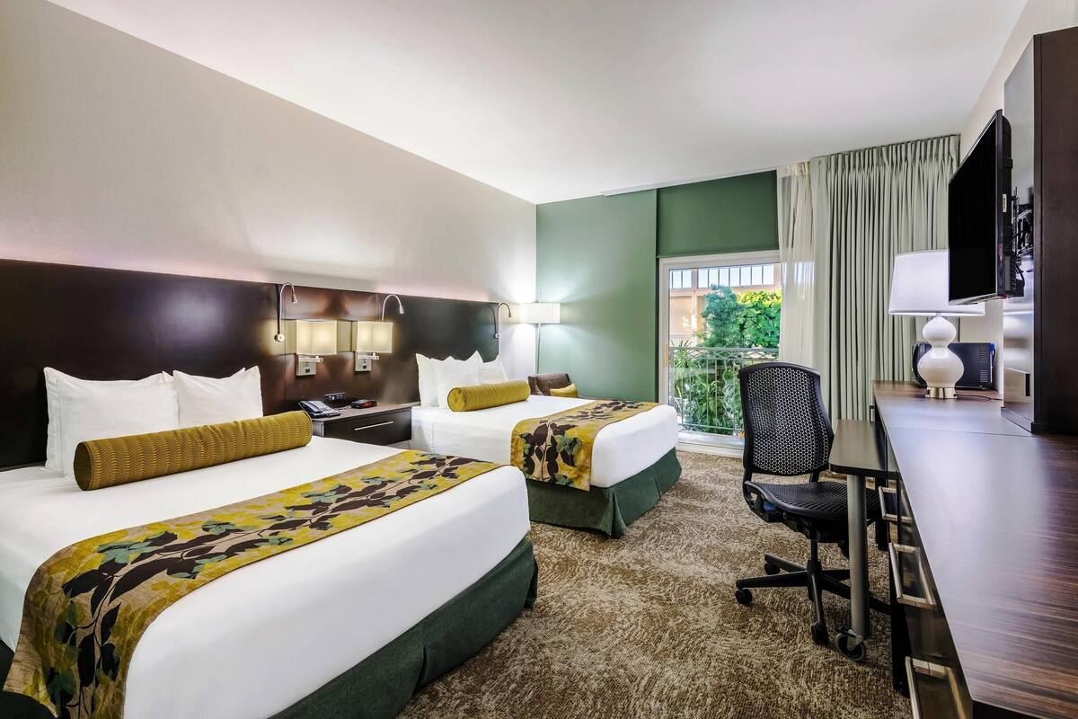 Habitación de hotel con dos camas, un escritorio y un televisor.