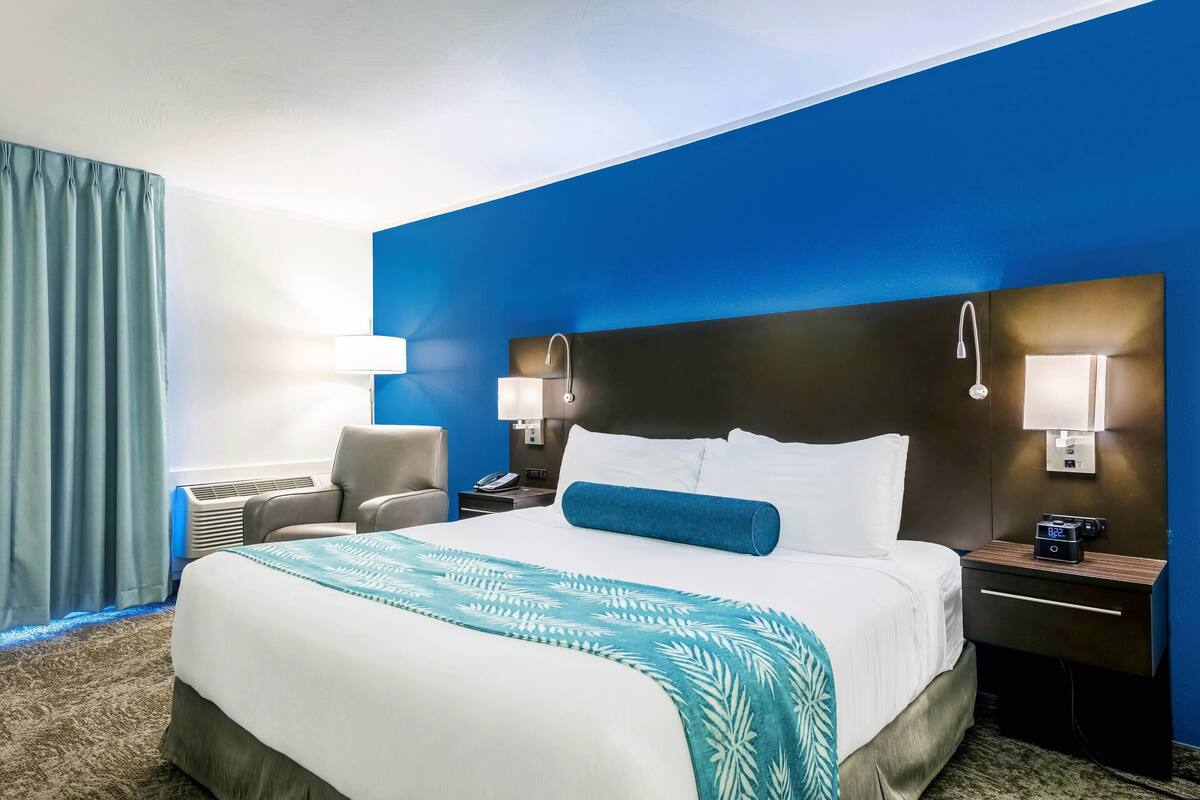 Habitación de hotel con una cama grande, dos mesitas de noche, una silla y un escritorio.
