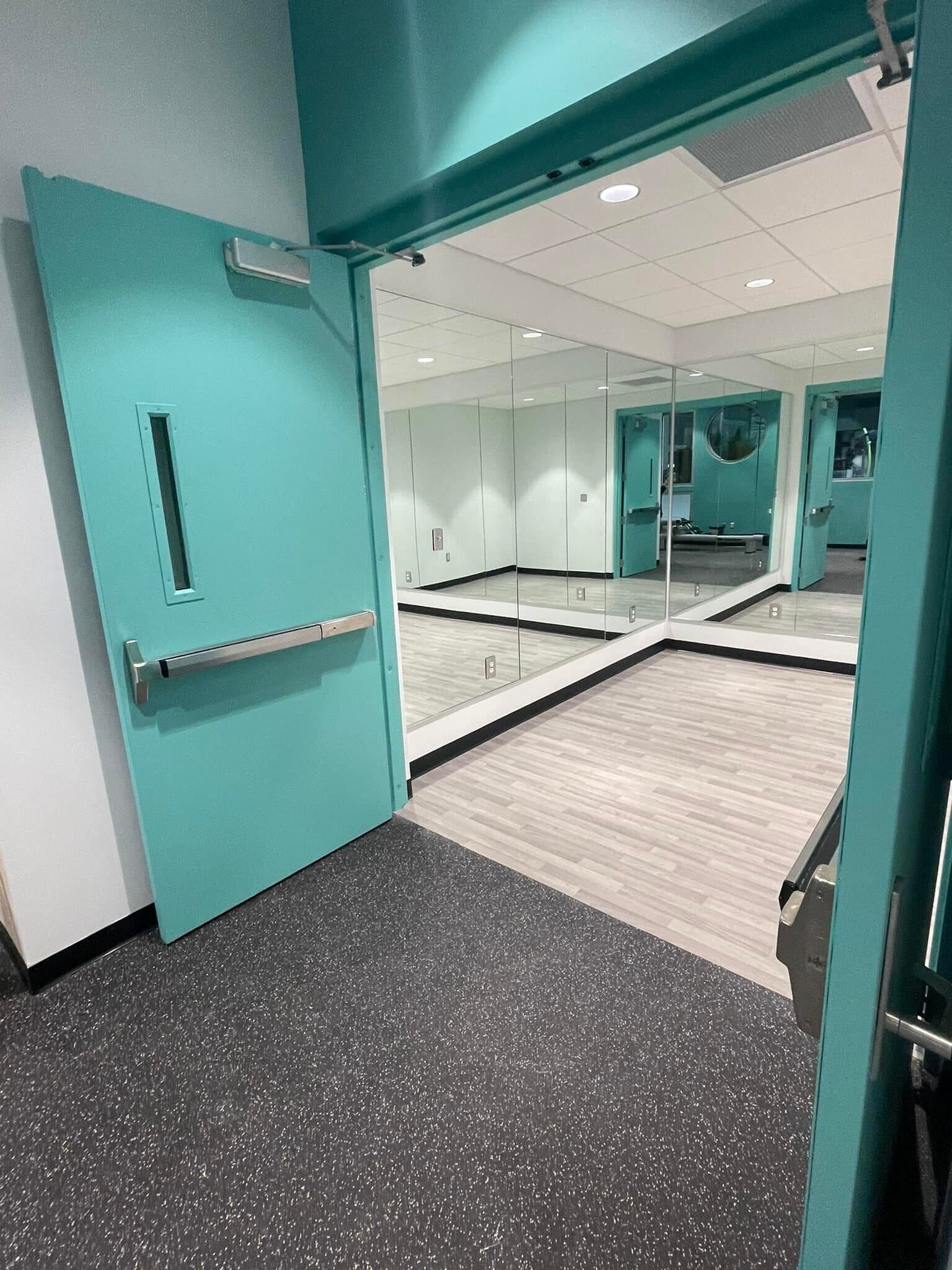 Een moderne kamer met turquoise wanden, een glazen deur en een spiegelwand.