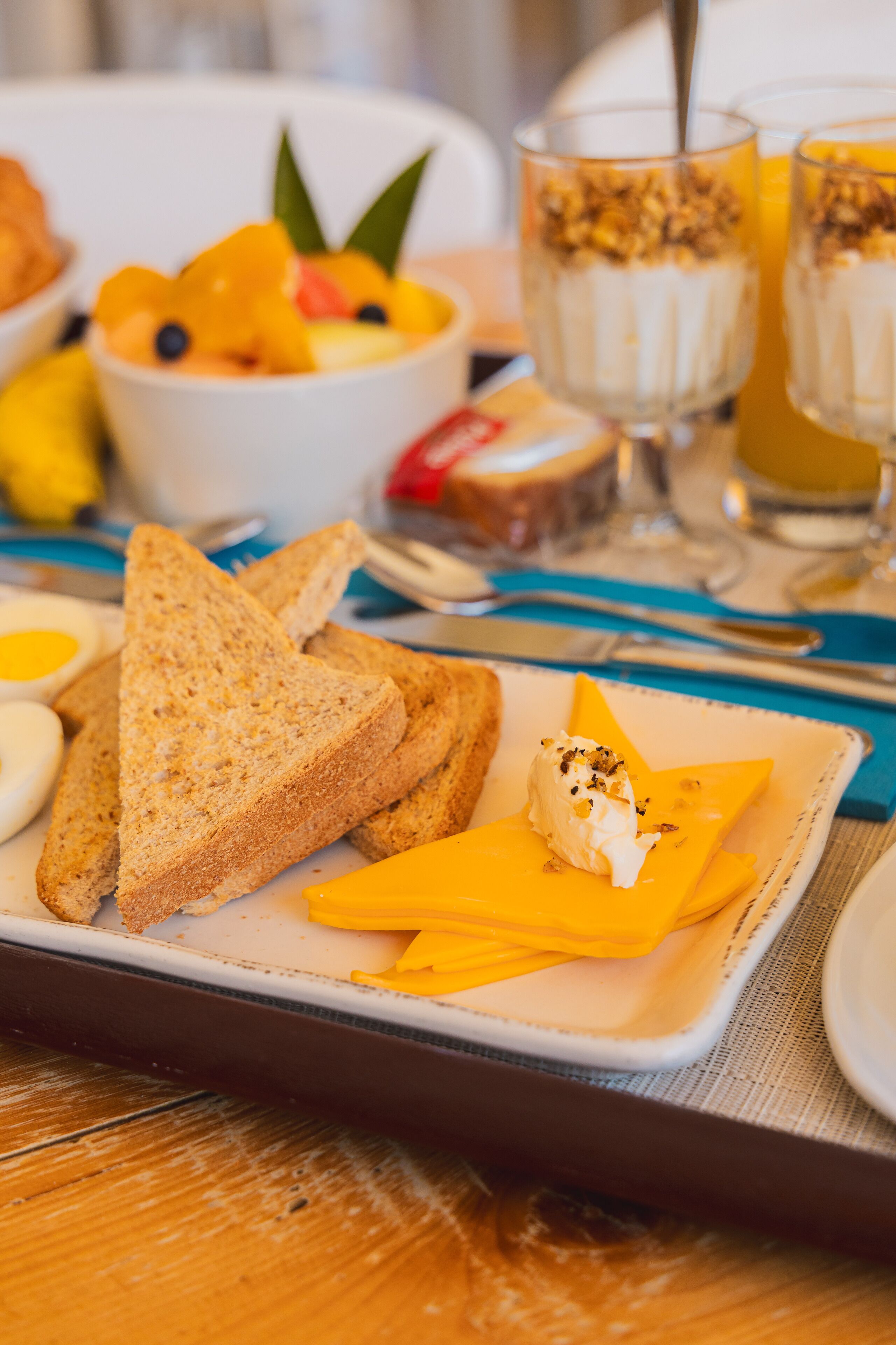 Desayuno con tostadas, huevos, queso y fruta sobre una bandeja.