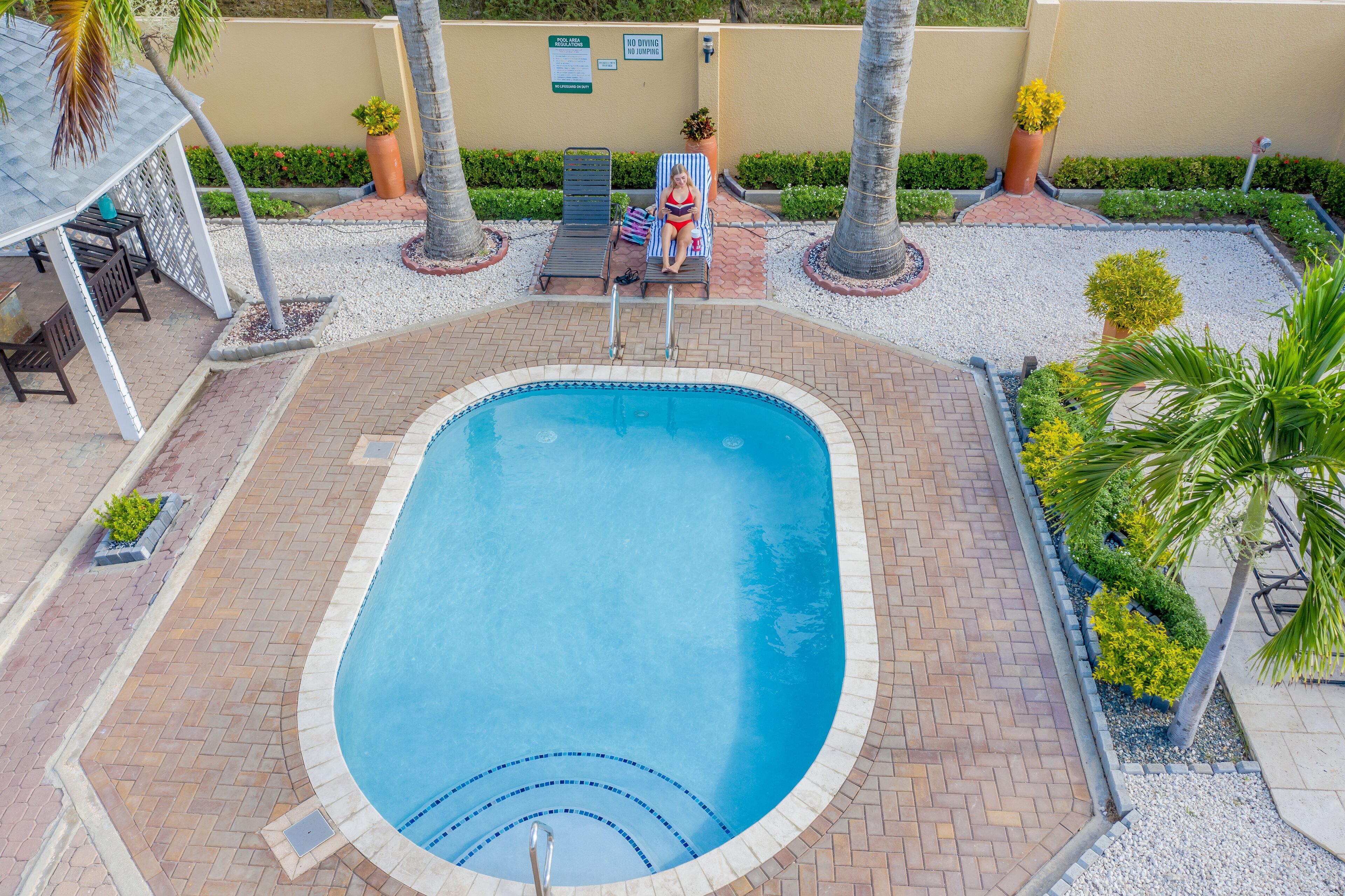 A swimming pool with lounge chairs and a covered seating area.