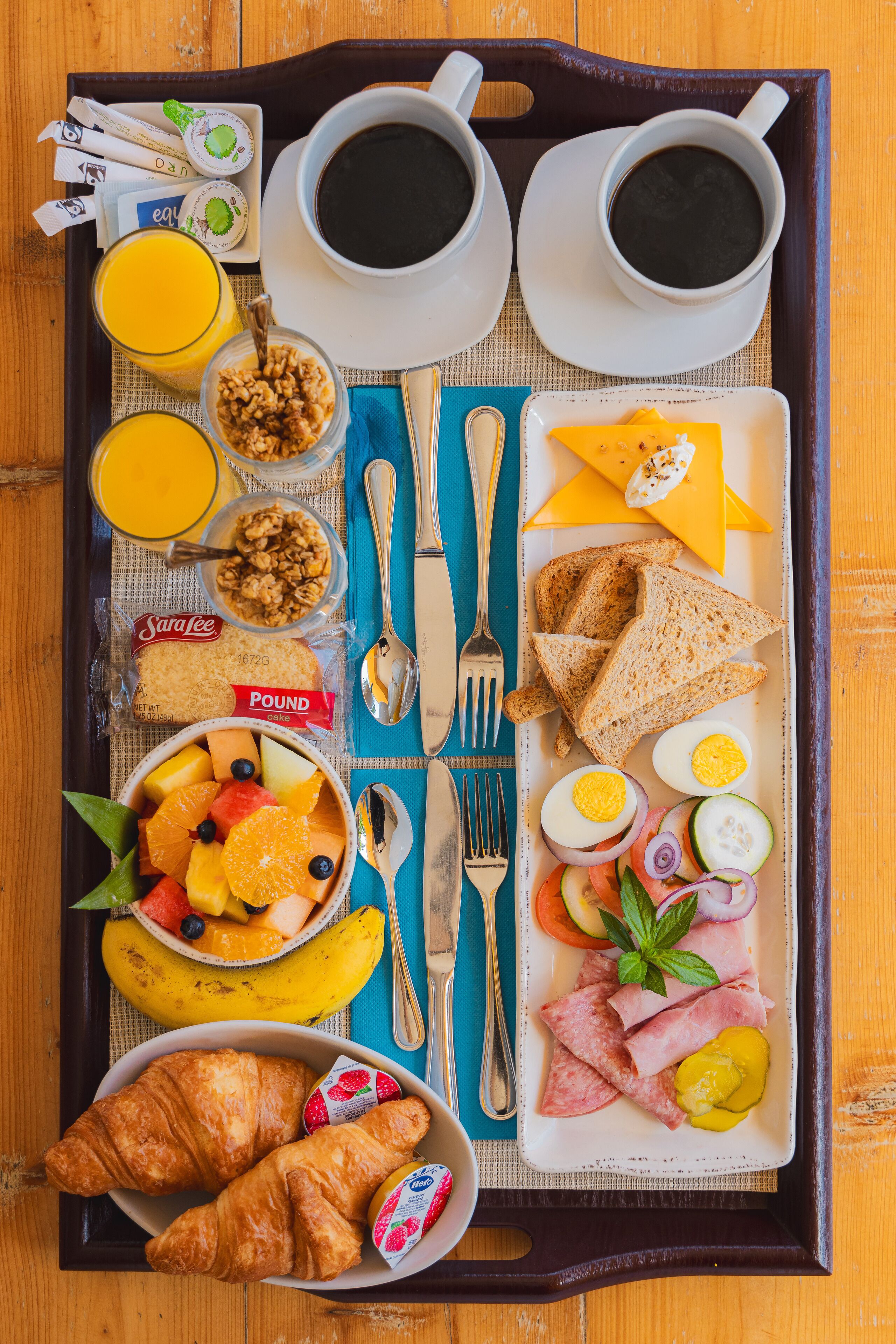 Een ontbijfwagen met croissants, eieren, kaas, ham en fruit.