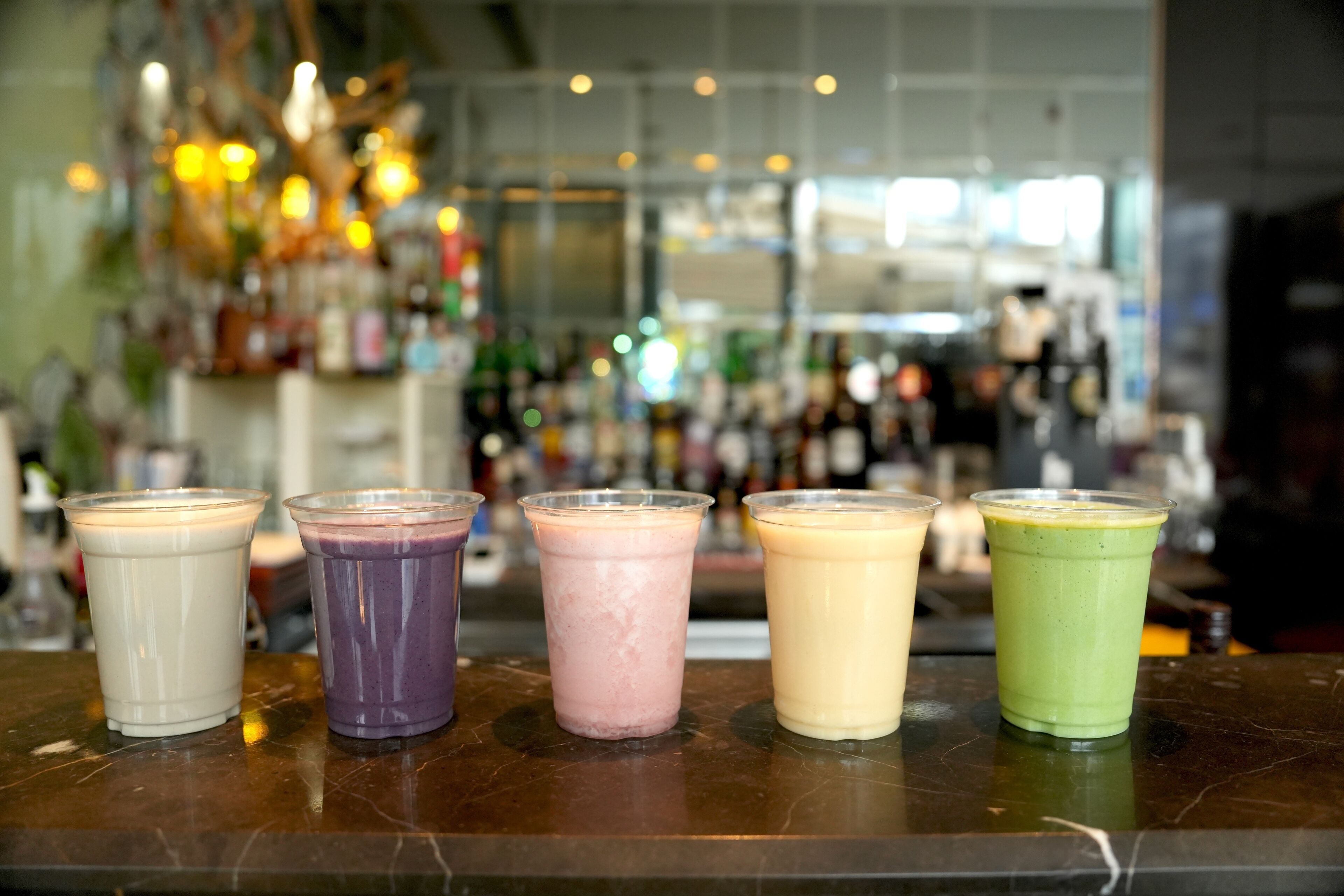 Un comptoir de bar avec cinq boissons aux couleurs vives.