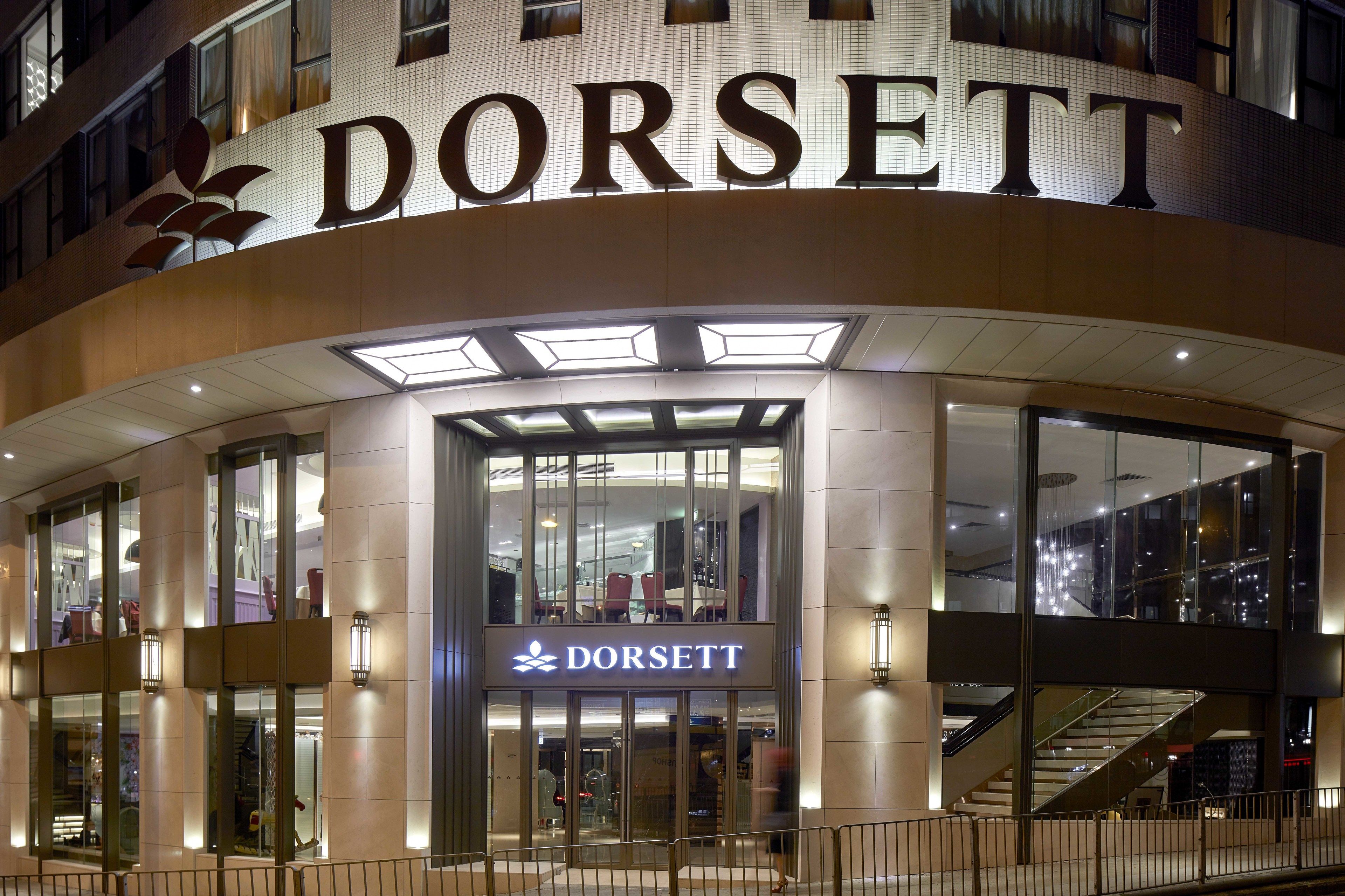 L’entrée d’un hôtel DORSETT, avec une façade en verre, un escalier apparent et un design moderne.