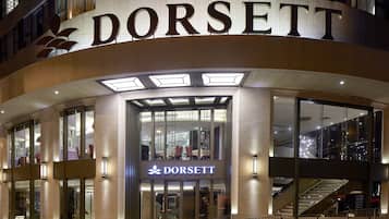 L’entrée d’un hôtel DORSETT, avec une façade en verre, un escalier apparent et un design moderne.