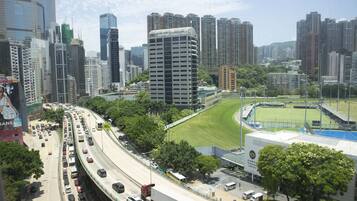 A cityscape with high-rise buildings, a highway, and a sports field.