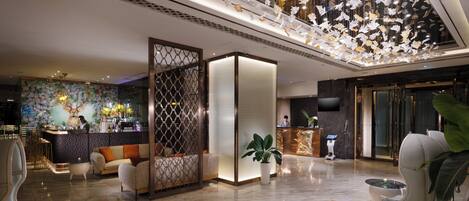 A spacious lobby with a reception desk, seating area, and a decorative ceiling.