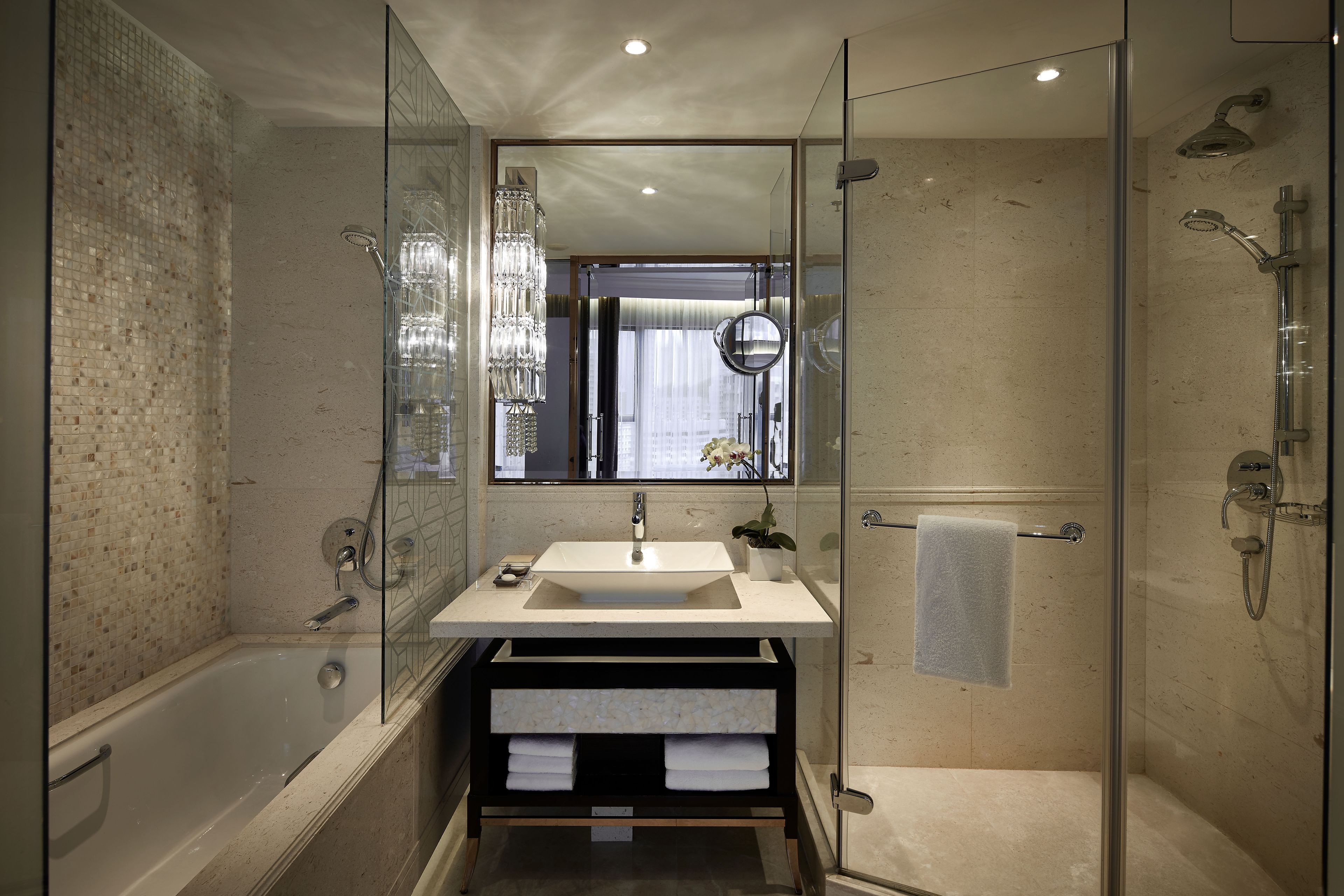 Een moderne badkamer met een glazen douchecabine, een vrijstaand bad en een wastafel met een grote spiegel.