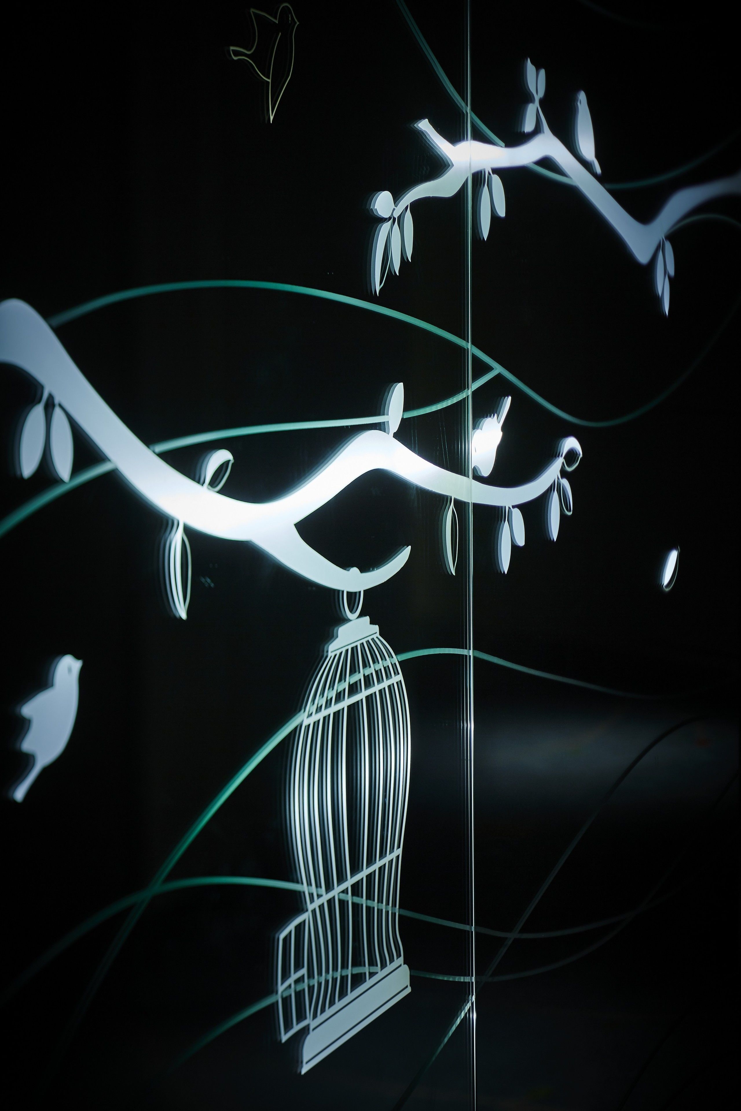 A stylized tree branch with a birdcage hanging from it.