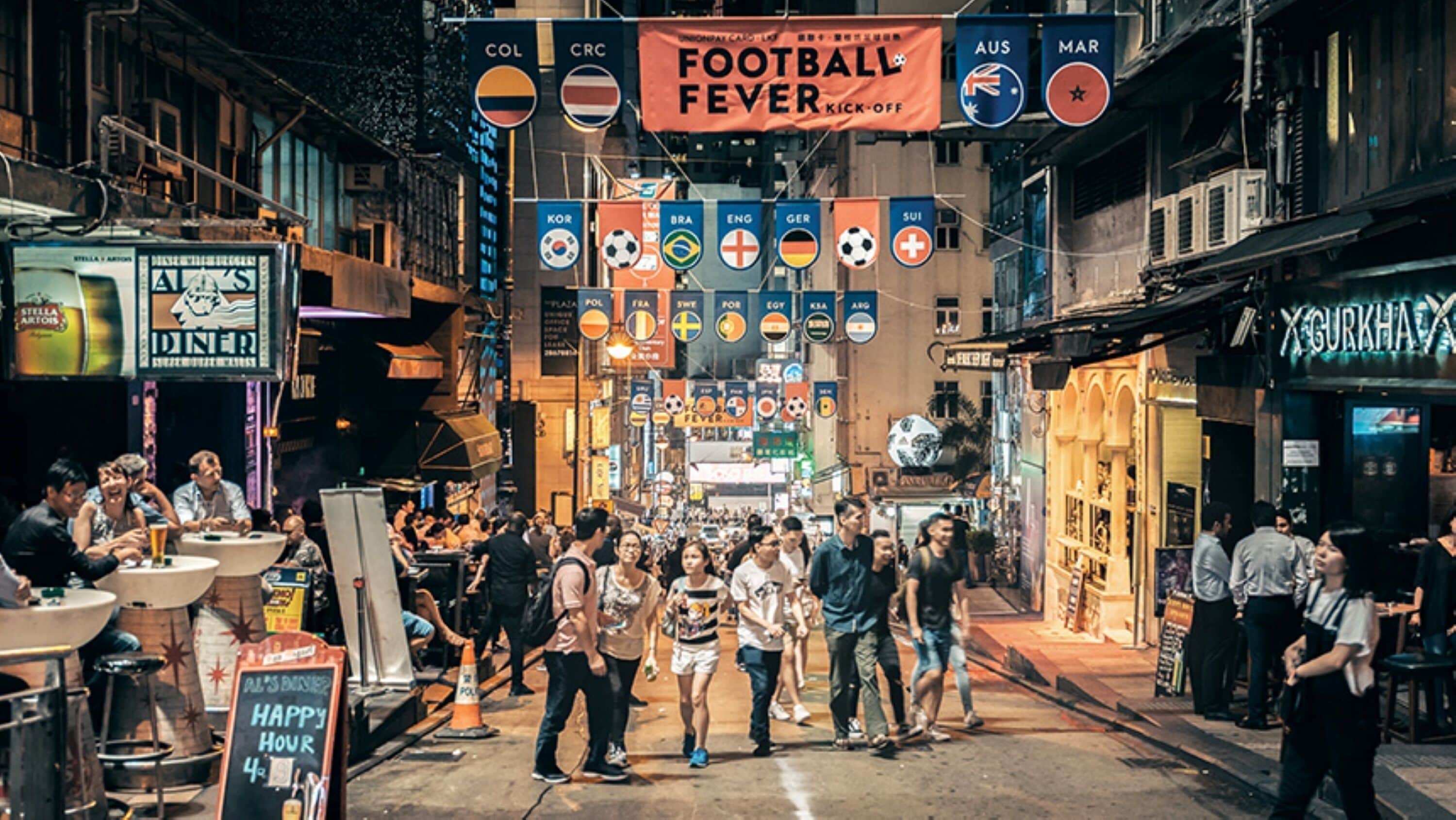 A busy street with people walking, dining, and shops.