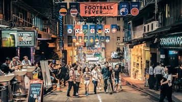 Een levendige straat met mensen die wandelen, uit eten gaan en winkels.