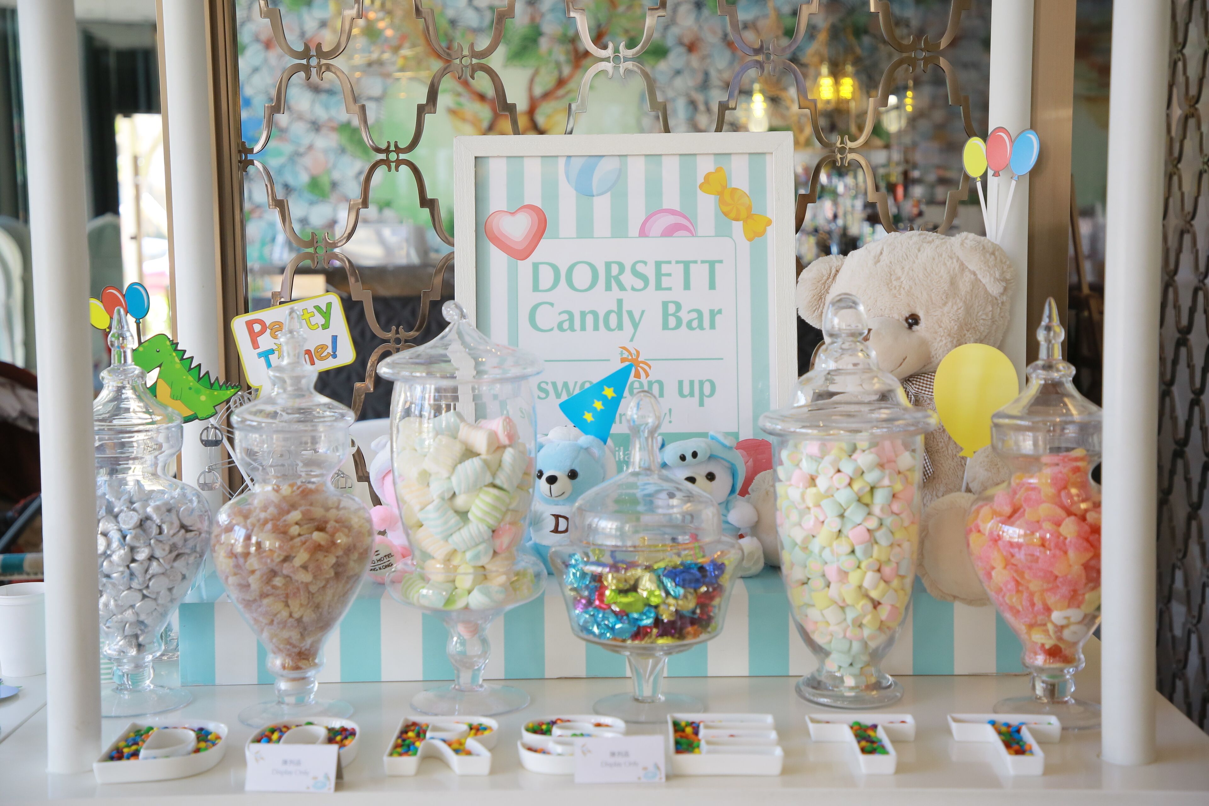 Een snoepbar met verschillende potten vol snoep en een bordje met de tekst 'DORSETT Candy Bar'.