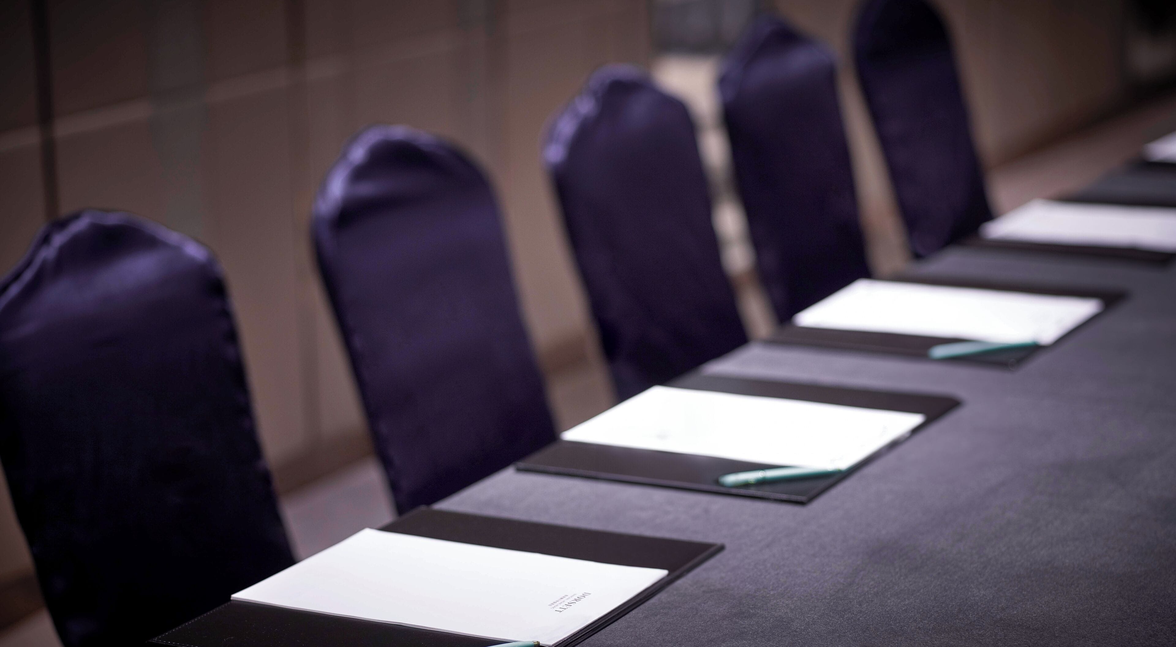 A conference room with a long table, chairs, and name cards.