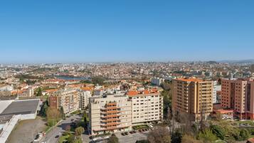 Un edificio de gran altura con varios pisos y balcones, rodeado de otros edificios y un cielo despejado.