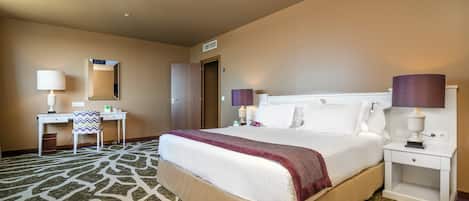 A hotel room with a large bed, a desk, a chair, and two bedside lamps.