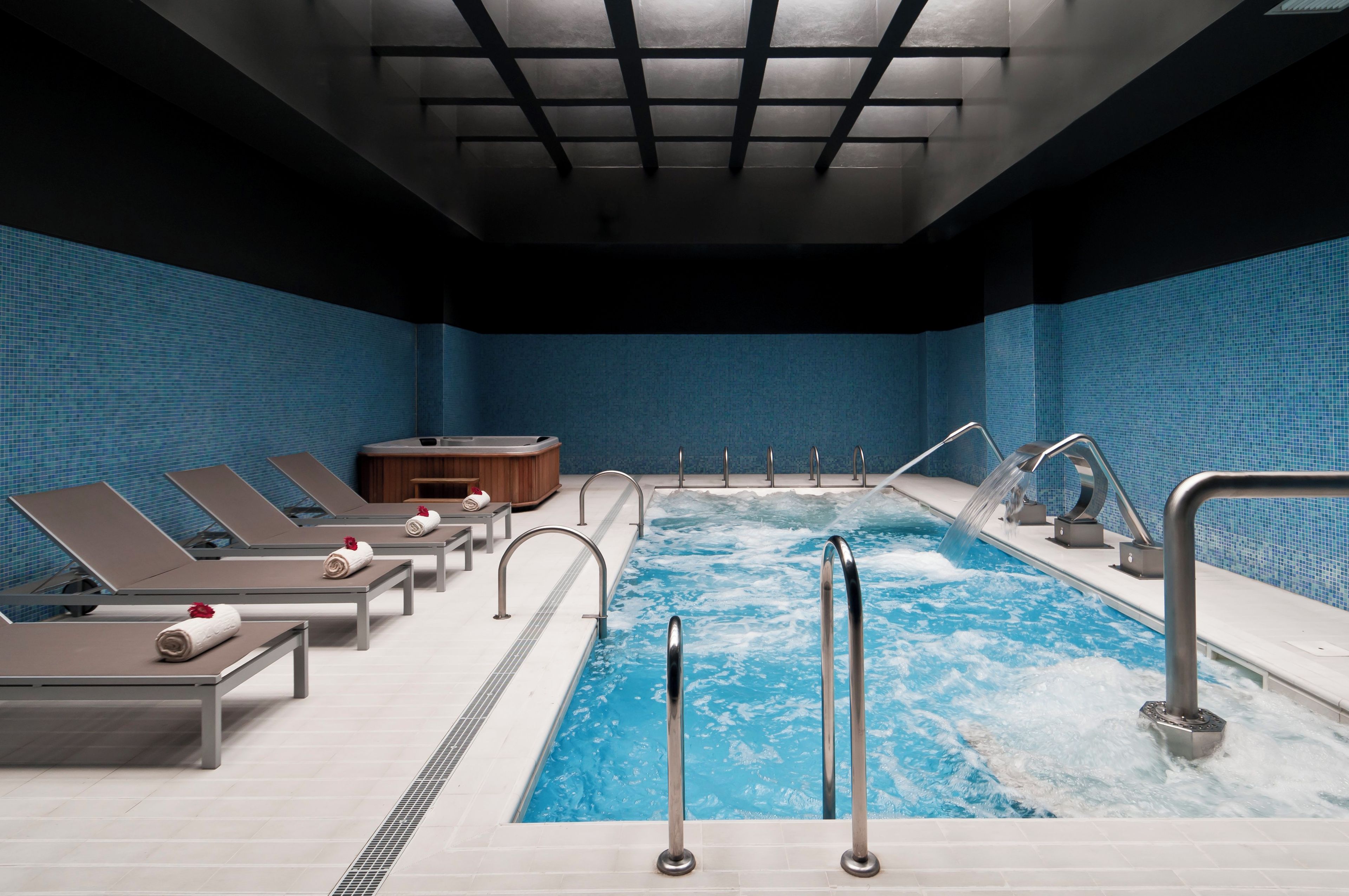 Ein modernes Hallenbad mit mehreren Bahnen, Liegestühlen und einem Whirlpool.