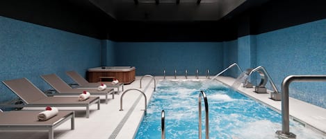 Ein modernes Hallenbad mit mehreren Bahnen, Liegestühlen und einem Whirlpool.