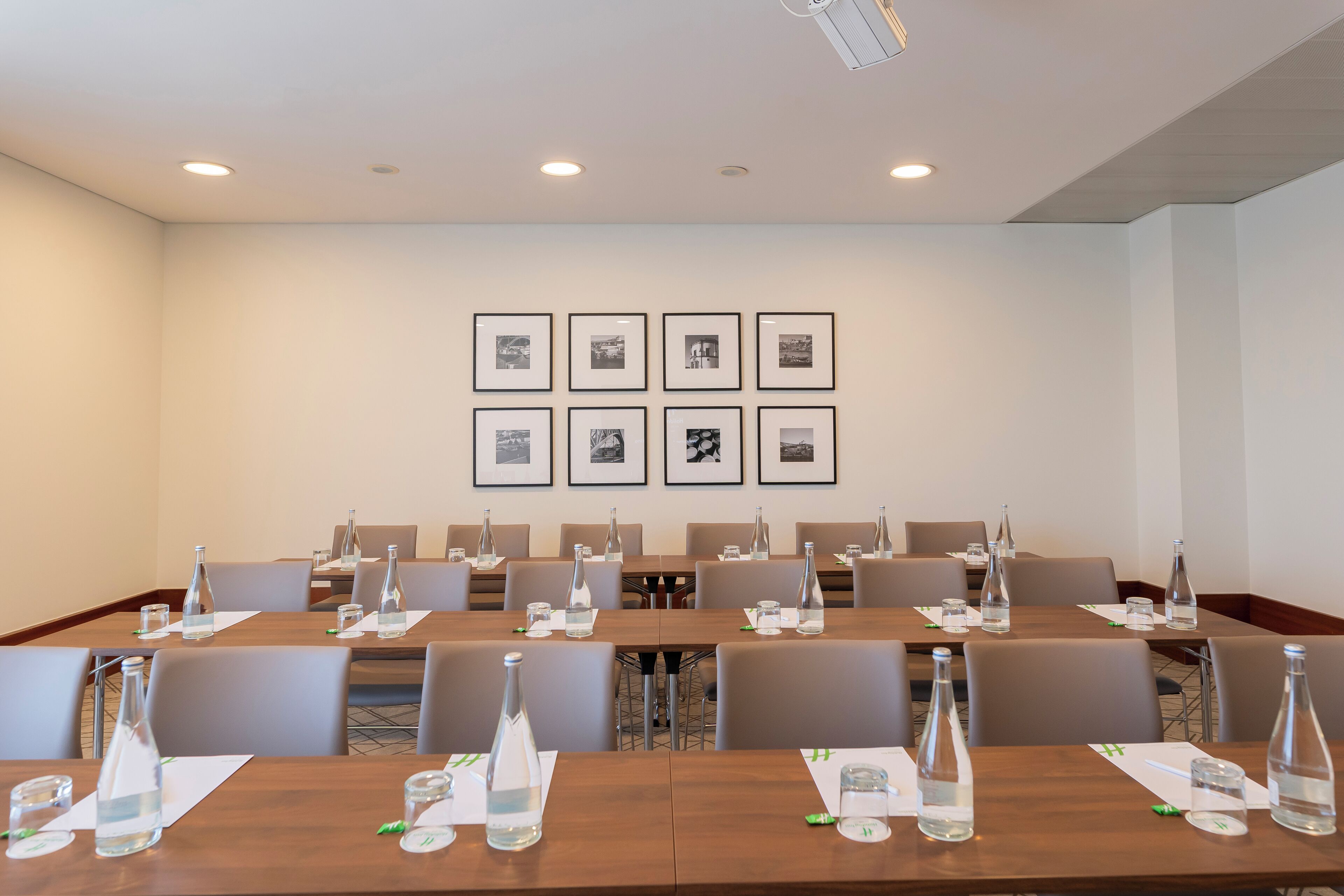 A conference room with multiple tables, each equipped with water bottles and glasses, and framed pictures on the wall.
