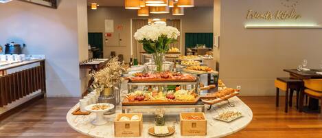A buffet setup with various food items and a central floral arrangement on a marble table.