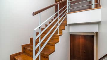Eine moderne Treppe mit Holzsitzstufen und einem Metallgeländer, die zu einer Zwischenebene mit einer Holztür führt.