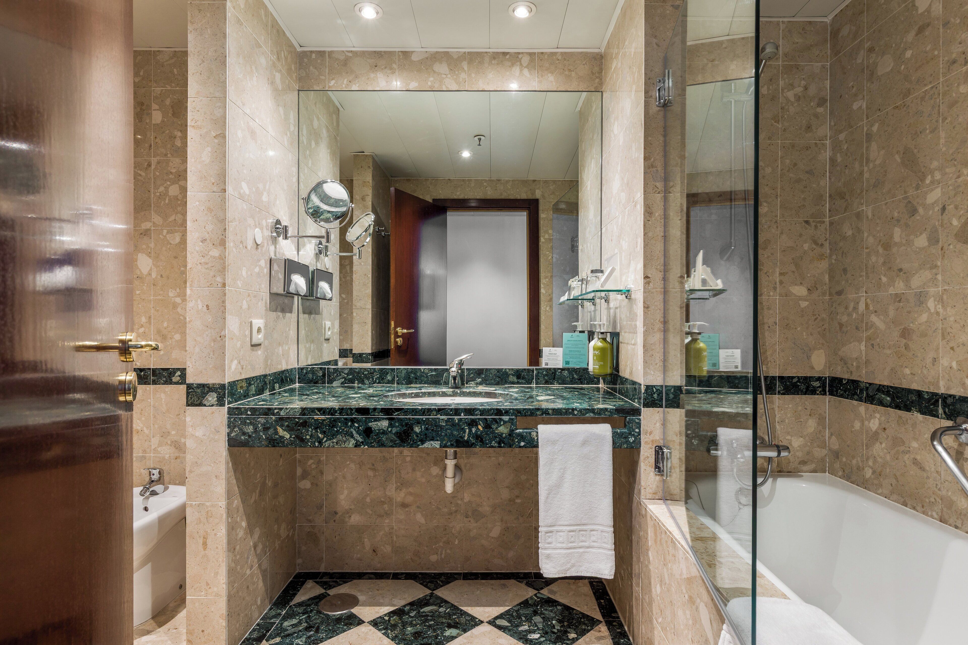 Ein modernes Badezimmer mit Duschkabine aus Glas, Waschbecken mit Marmorplatte und einer Badewanne.