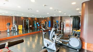 Un gimnasio con diverso equipo de ejercicio, un espejo grande y un suelo pulido.