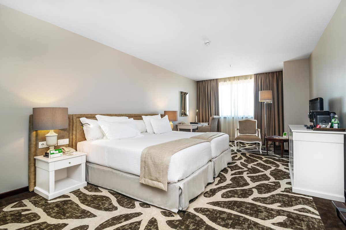 Une chambre d’hôtel dotée d’un grand lit, d’un bureau, d’une chaise, d’un mini-bar et offrant une vue sur l’extérieur.