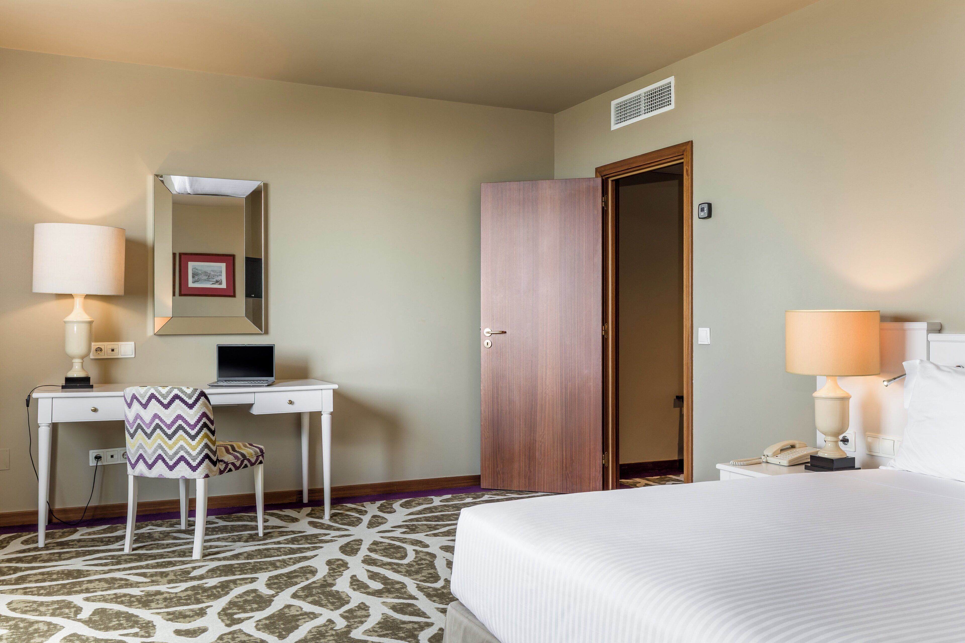 Habitación de hotel con cama, escritorio, silla y armario.