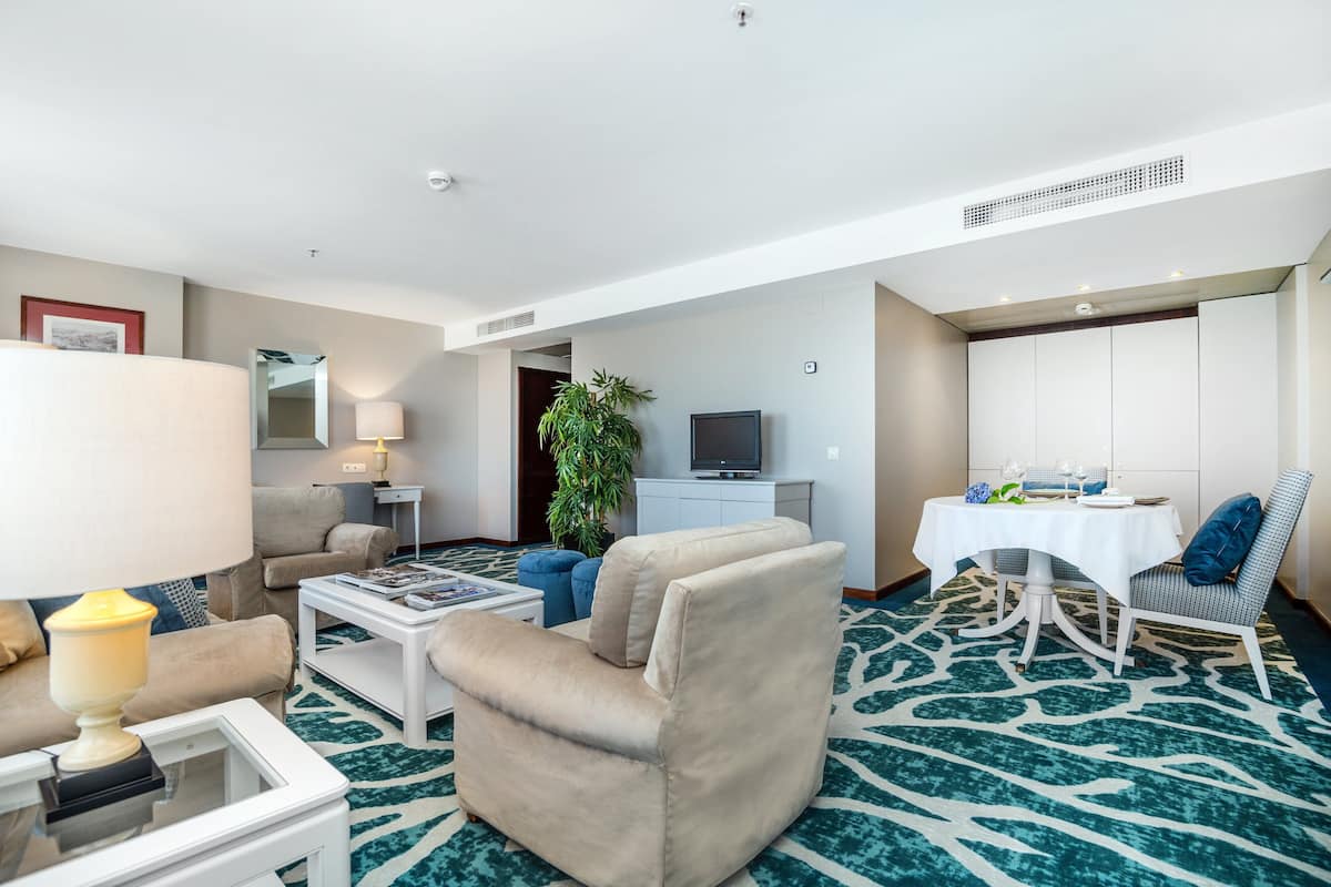 Une chambre d’hôtel comprenant un coin salon, une table à manger, une télévision et un minibar.
