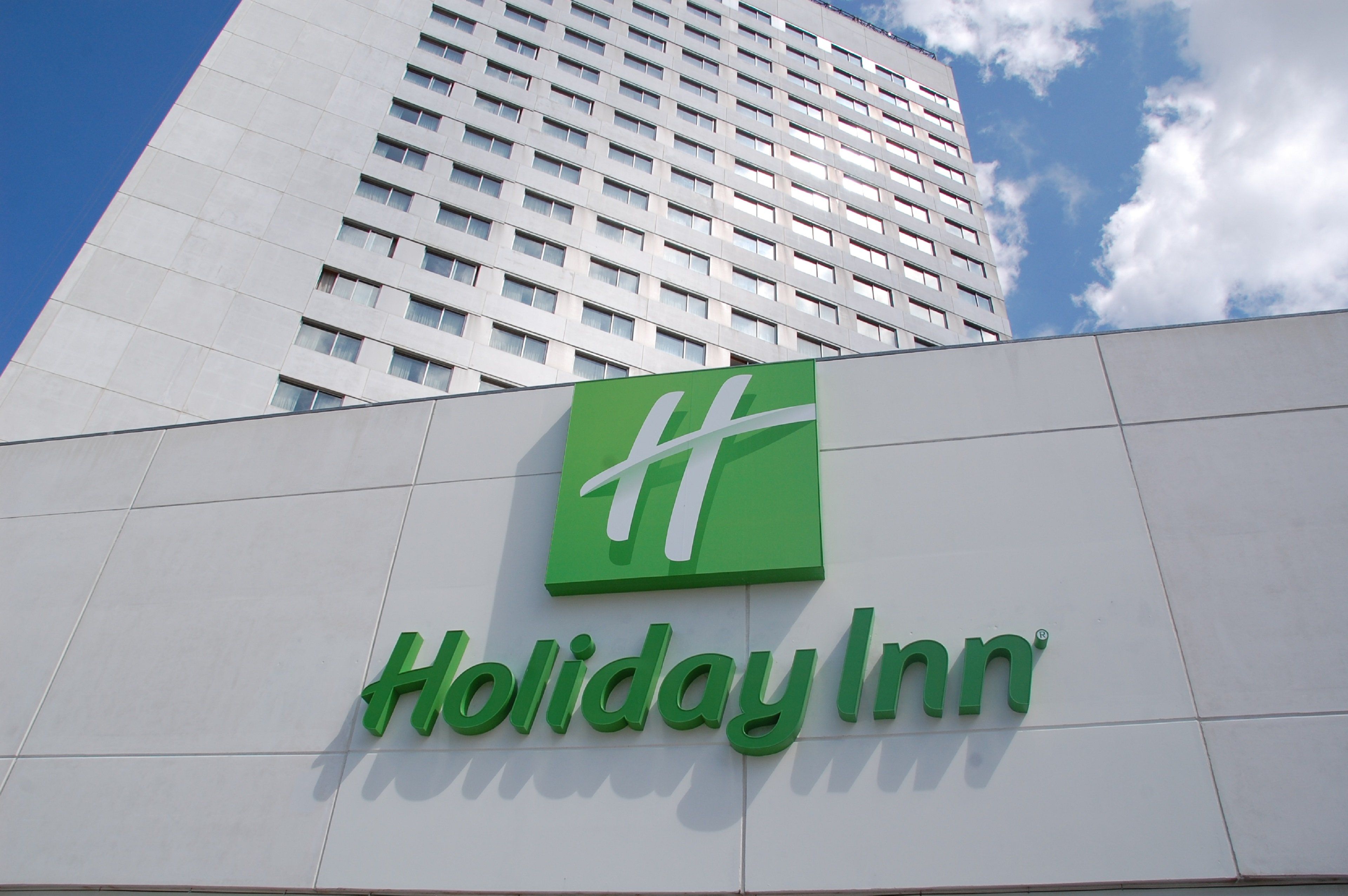 A Holiday Inn sign on a building with a modern design and a clear sky in the background.