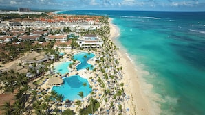 Ein Resort mit mehreren Schwimmbecken, einem Strand und Blick aufs Meer.