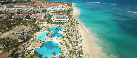 A resort with multiple swimming pools, a beach, and a view of the ocean.