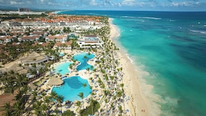 A resort with multiple swimming pools, a beach, and a view of the ocean.