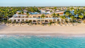 A beachfront hotel with multiple buildings, a sandy beach, and ocean waves.