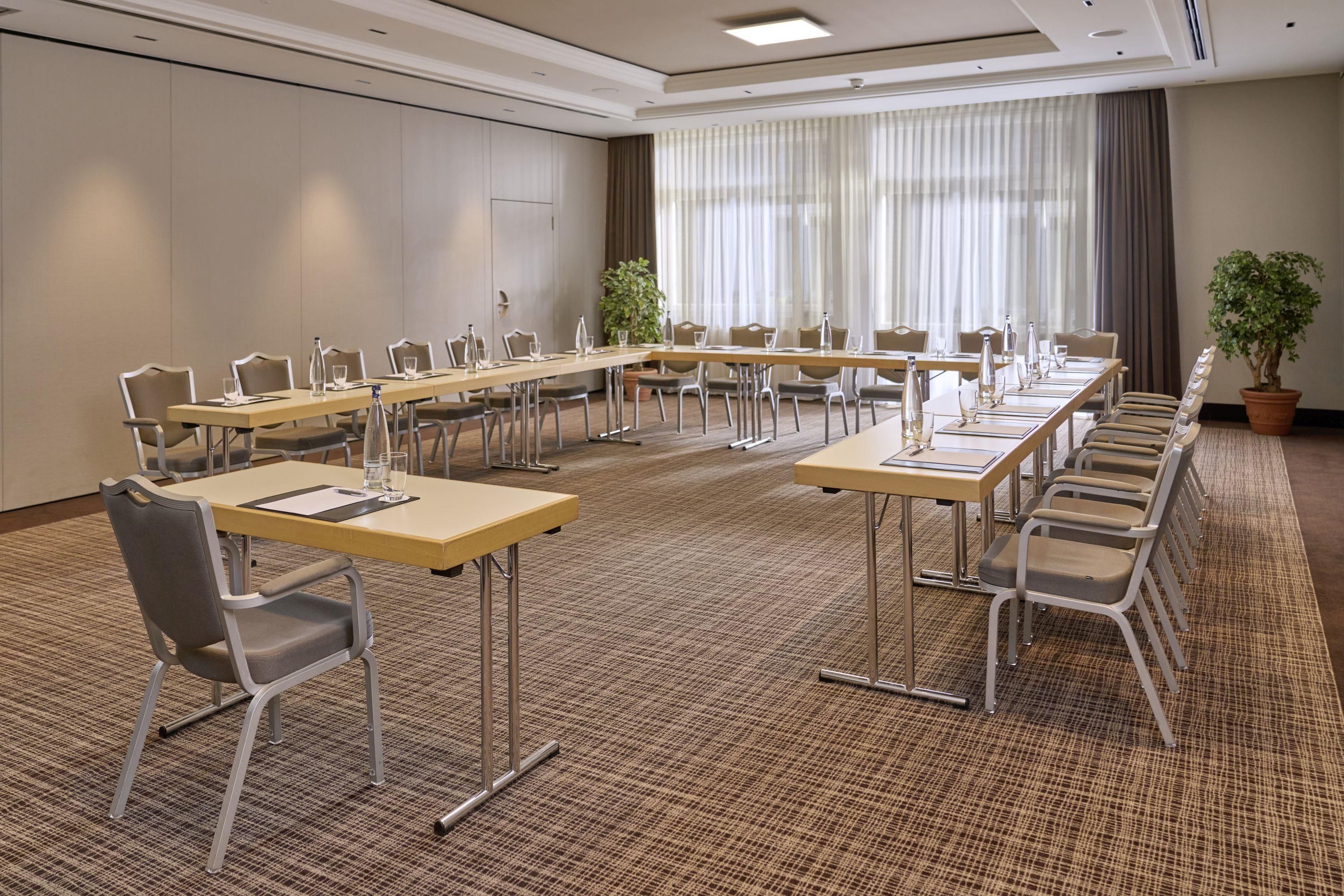 A conference room with a long table, chairs, and a carpeted floor.