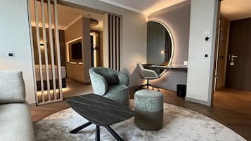 A modern living room with a sofa, a coffee table, and a chair. There is a mirror on the wall and a door leading to another room.