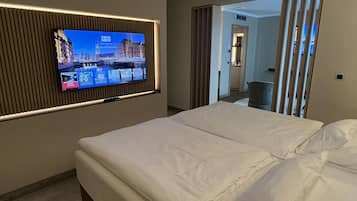 A hotel room with a bed, a television mounted on the wall, and a view of the hallway.