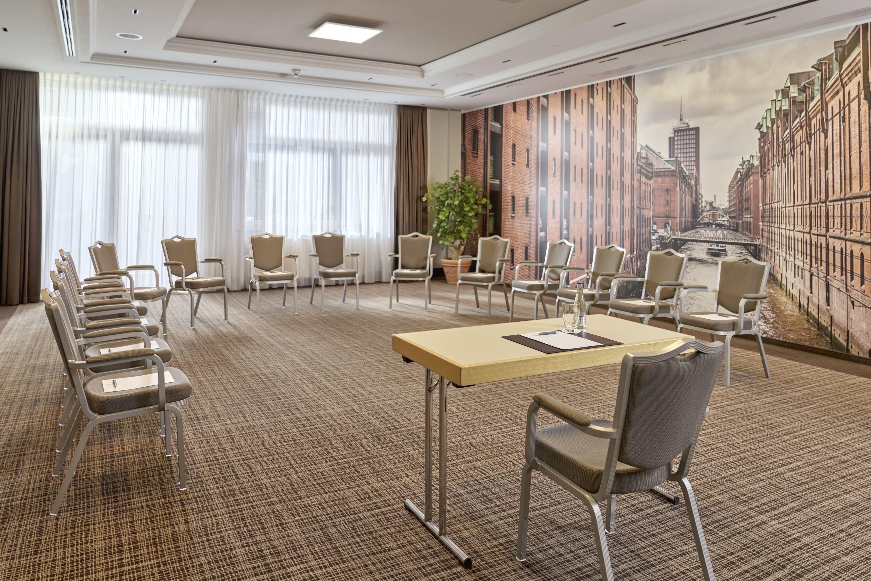 A conference room with a long table, multiple chairs, and a cityscape mural on the wall.